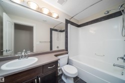 Full bathroom featuring a dark wood-finish vanity with an integrated sink, polished chrome faucet, and a large wall-mounted mirror - 