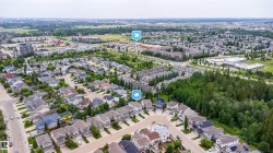 Aerial perspective showcasing a residential area with varied housing styles, surrounded by green spaces and mature trees - 