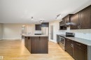 Contemporary kitchen featuring dark wood cabinetry, stainless steel appliances, and light countertops - 11312 13 Ave Sw, Edmonton, AB 