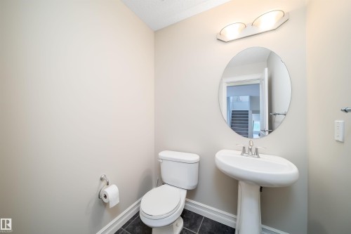Pedestal sink with chrome faucet, oval mirror, and overhead vanity lighting - 11312 13 Ave Sw, Edmonton, AB 