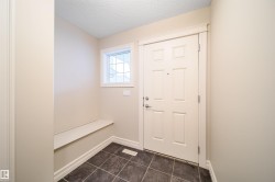 Entryway featuring a paneled door, square tile flooring, built-in bench, and a transom window - 