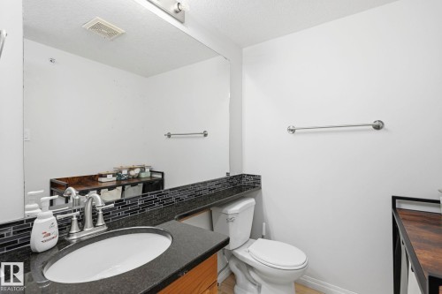 Bathroom with a vanity featuring a dark countertop, an integrated sink, and a chrome faucet - 426 3425 19 Street, Edmonton, AB 