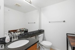 Bathroom with a vanity featuring a dark countertop, an integrated sink, and a chrome faucet - 