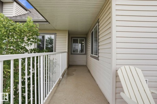 Covered outdoor balcony featuring a white railing, siding exterior, and durable concrete surface - 426 3425 19 Street, Edmonton, AB 