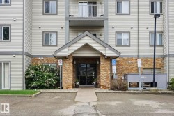 Multi-story building exterior featuring light-colored siding and stone veneer accents - 