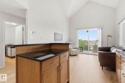 Open-concept living space featuring wood-finish flooring and vaulted ceilings - 