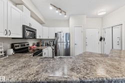 Kitchen featuring extensive countertop space, white cabinetry, stainless steel refrigerator, black range, and built-in microwave - 