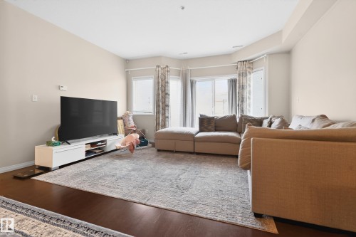 Spacious living area featuring rich wood-finish flooring, light-toned walls, and a recessed ceiling - 226 4304 139 Avenue, Edmonton, AB 