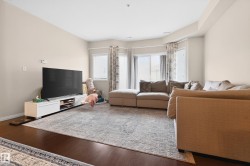 Spacious living area featuring rich wood-finish flooring, light-toned walls, and a recessed ceiling - 