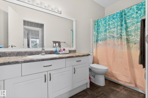Bathroom vanity featuring white cabinetry, an integrated sink, and a speckled countertop - 226 4304 139 Avenue, Edmonton, AB 