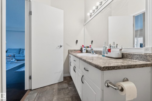 Bathroom vanity featuring a single basin sink, laminate countertop, and white cabinetry with dark hardware - 226 4304 139 Avenue, Edmonton, AB 