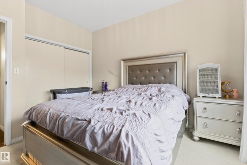 Bedroom featuring neutral-toned walls, light-colored carpeting, and a built-in closet with sliding doors - 226 4304 139 Avenue, Edmonton, AB 