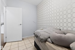 Room featuring a decorative accent wall with a geometric circular pattern, light-toned tile flooring, and a white interior door with a chrome handle - 