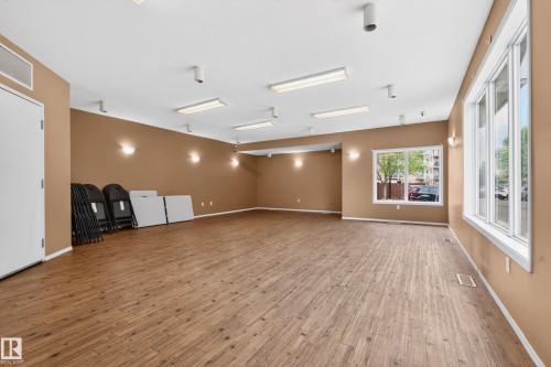 Spacious room with wood-finish flooring, multiple large windows, recessed lighting, wall sconces, and neutral wall paint - 226 4304 139 Avenue, Edmonton, AB 