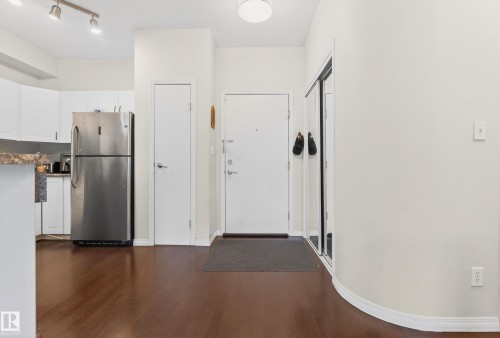 Entry foyer featuring wood-finish flooring, a white entry door, and a mirrored closet - 226 4304 139 Avenue, Edmonton, AB 