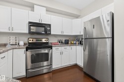 Kitchen featuring white cabinetry, wood-finish flooring, stainless steel appliances, and light-colored countertops - 