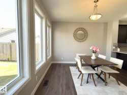 Dining area with wood-finish flooring, light grey wall paint, and a row of four tall windows - 