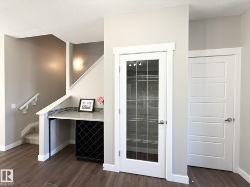 Built-in desk area with a stone-finish countertop, integrated wine rack, and wood-finish flooring - 3110 Paisley Road, Edmonton, AB 