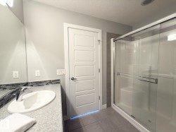 Bathroom featuring a vanity with an undermount sink and chrome faucet, mosaic tile backsplash, and a glass-enclosed shower with sliding doors - 