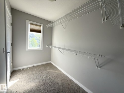 Carpeted interior space with a window featuring a blind, white trim, and a white interior door - 3110 Paisley Road, Edmonton, AB 