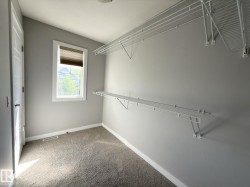 Carpeted interior space with a window featuring a blind, white trim, and a white interior door - 