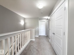 Upper level hallway featuring light gray wall paint, white trim, and light gray carpeted flooring - 