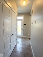 Entryway featuring tile flooring, a frosted glass door with transom window, and a built-in closet with paneled doors - 
