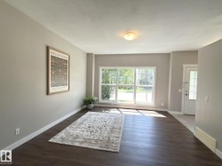 Spacious living area featuring wood-finish flooring, neutral wall tones, and a large picture window - 