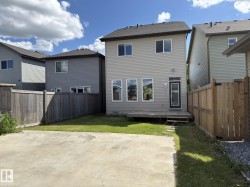 Rear exterior featuring a ground-level wood deck, a rear entry door with a full-lite insert, horizontal siding, and multiple windows - 