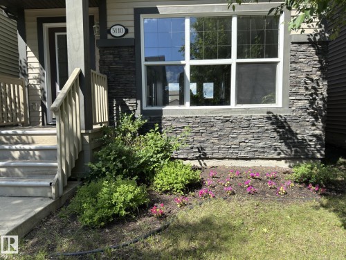 Exterior facade featuring stacked stone accents, horizontal siding, and a prominent front window with grid panes - 3110 Paisley Road, Edmonton, AB 