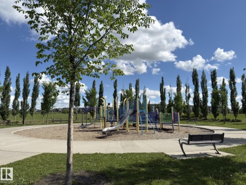 Community park featuring a children's play structure, curved paved pathways, and mature trees - 3110 Paisley Road, Edmonton, AB 