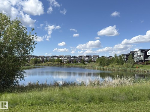 Expansive pond with natural grasses and foliage, bordered by a row of residential properties - 3110 Paisley Road, Edmonton, AB 