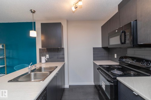 Contemporary kitchen featuring dark cabinetry, light countertops, and a subway tile backsplash - 431 344 Windermere Road, Edmonton, AB - Indoor Photo Showing Kitchen With Double Sink