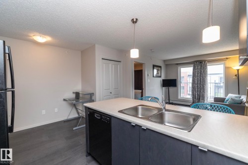 Contemporary kitchen island featuring a double stainless steel sink and integrated dishwasher - 431 344 Windermere Road, Edmonton, AB - Indoor Photo Showing Kitchen With Double Sink