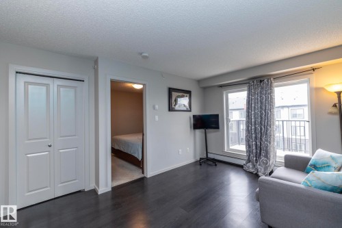 Dark wood-finish flooring throughout the main living area - 431 344 Windermere Road, Edmonton, AB - Indoor Photo Showing Living Room