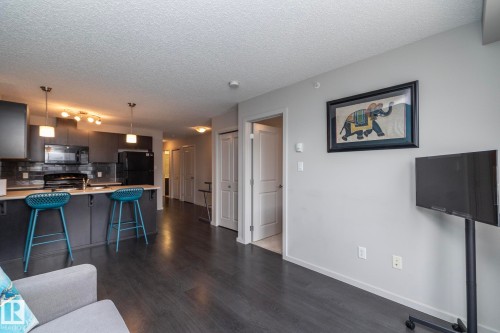 Modern kitchen featuring dark cabinetry, stainless steel appliances, and a light-toned breakfast bar with pendant lighting - 431 344 Windermere Road, Edmonton, AB - Indoor
