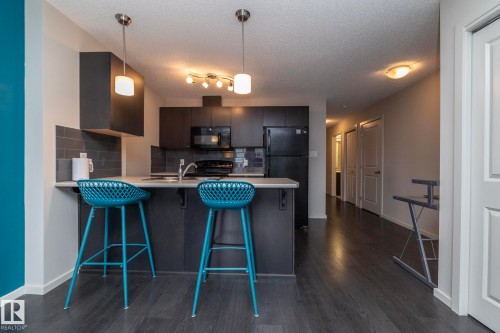 Modern kitchen featuring dark cabinetry, light countertops, and a subway tile backsplash - 431 344 Windermere Road, Edmonton, AB - Indoor Photo Showing Kitchen