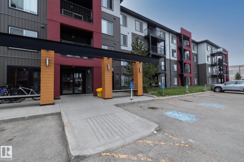 Modern multi-story building featuring a prominent main entrance with a concrete walkway, wood-finish columns, and exterior wall sconces - 431 344 Windermere Road, Edmonton, AB - Outdoor With Balcony