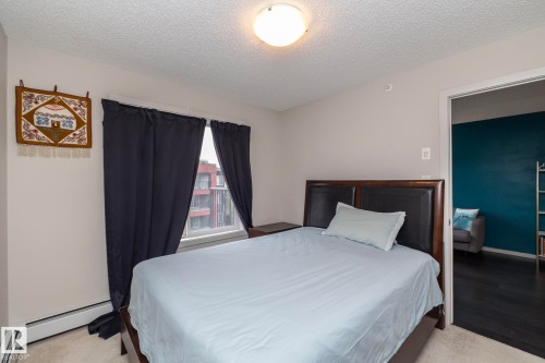 Neutral wall paint, a window with exterior views, and a baseboard heater define this interior space - 431 344 Windermere Road, Edmonton, AB - Indoor Photo Showing Bedroom