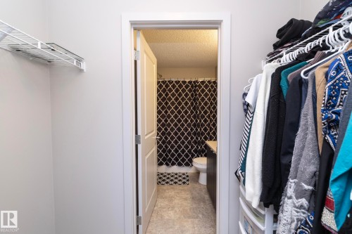 Walk-in closet featuring wire shelving and direct access to a bathroom with a shower-tub combination and vanity - 431 344 Windermere Road, Edmonton, AB - Indoor With Storage