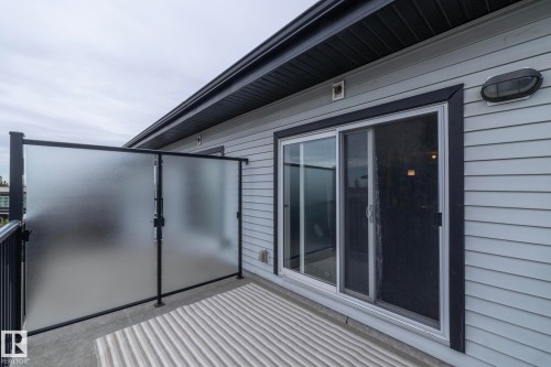 Private balcony featuring a frosted glass divider, light gray siding, and a sliding glass door with dark trim - 431 344 Windermere Road, Edmonton, AB - Outdoor With Exterior