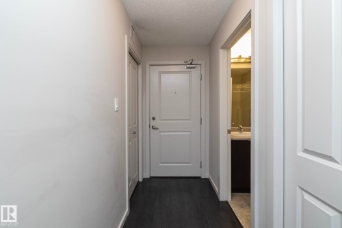 Entryway featuring dark wood-finish flooring, light grey walls, white paneled doors, and a built-in closet with bifold doors - 431 344 Windermere Road, Edmonton, AB - Indoor Photo Showing Other Room