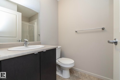 Contemporary bathroom featuring a dark wood-finish vanity with a light countertop and integrated sink, chrome faucet, and a large wall-mounted mirror - 431 344 Windermere Road, Edmonton, AB - Indoor Photo Showing Bathroom