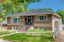 Bungalow exterior featuring a stucco and brick facade, dark shingle roof, and prominent front entry stairs with black metal railings - 11937 39 Street Nw, Edmonton, AB 