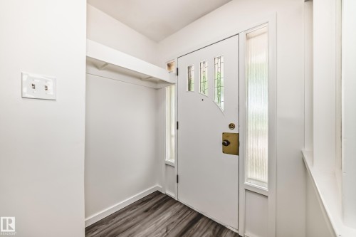 Entryway featuring a white door with decorative glass inserts, wood-finish flooring, and a built-in coat alcove with shelving - 11937 39 Street Nw, Edmonton, AB 