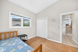 Room featuring wood-finish flooring, a vaulted ceiling, and a large window with white trim - 