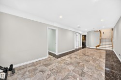 Spacious lower-level area featuring contrasting large format tile flooring, recessed lighting, white baseboards, and multiple doorways - 