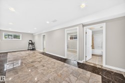 Spacious room featuring large format tile flooring with a contrasting border, recessed lighting, and a window providing natural light - 