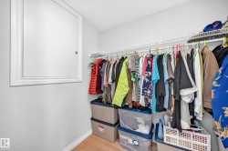 Walk-in closet featuring light wood-finish flooring, white walls, and a white access panel - 