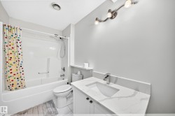 Bathroom featuring a white vanity with a marble-look countertop, undermount sink, and chrome faucet - 
